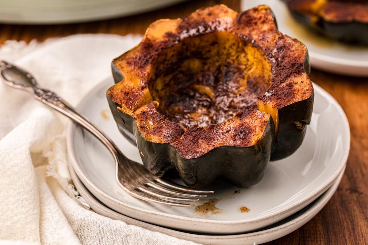 Come Cucinare la Zucca Delica nella Pentola a Cottura Lenta 8 Primo piano di mezza zucca Delica cotta lentamente su un piatto con una forchetta.