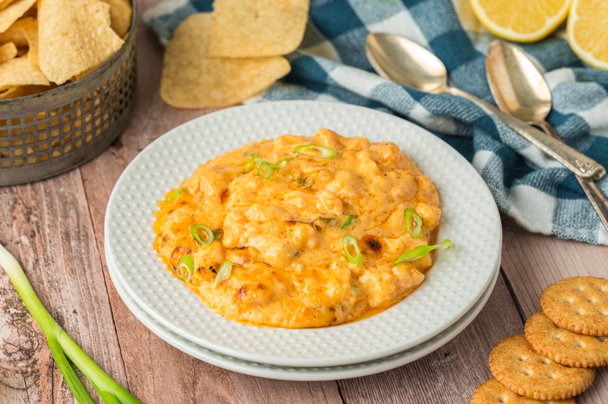 Salsa di Gamberetti Calda a Lenta Cottura 8 serving of slow cooker hot shrimp dip on a stack of plates.