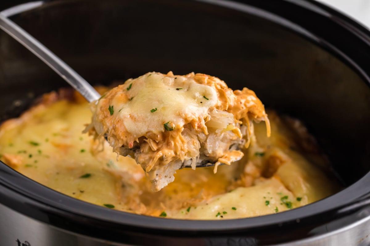 Casseruola di Pollo alla Reuben a Cottura Lenta 8 Cucchiaio con sformato di pollo Reuben in slow cooker sopra una pentola a cottura lenta.