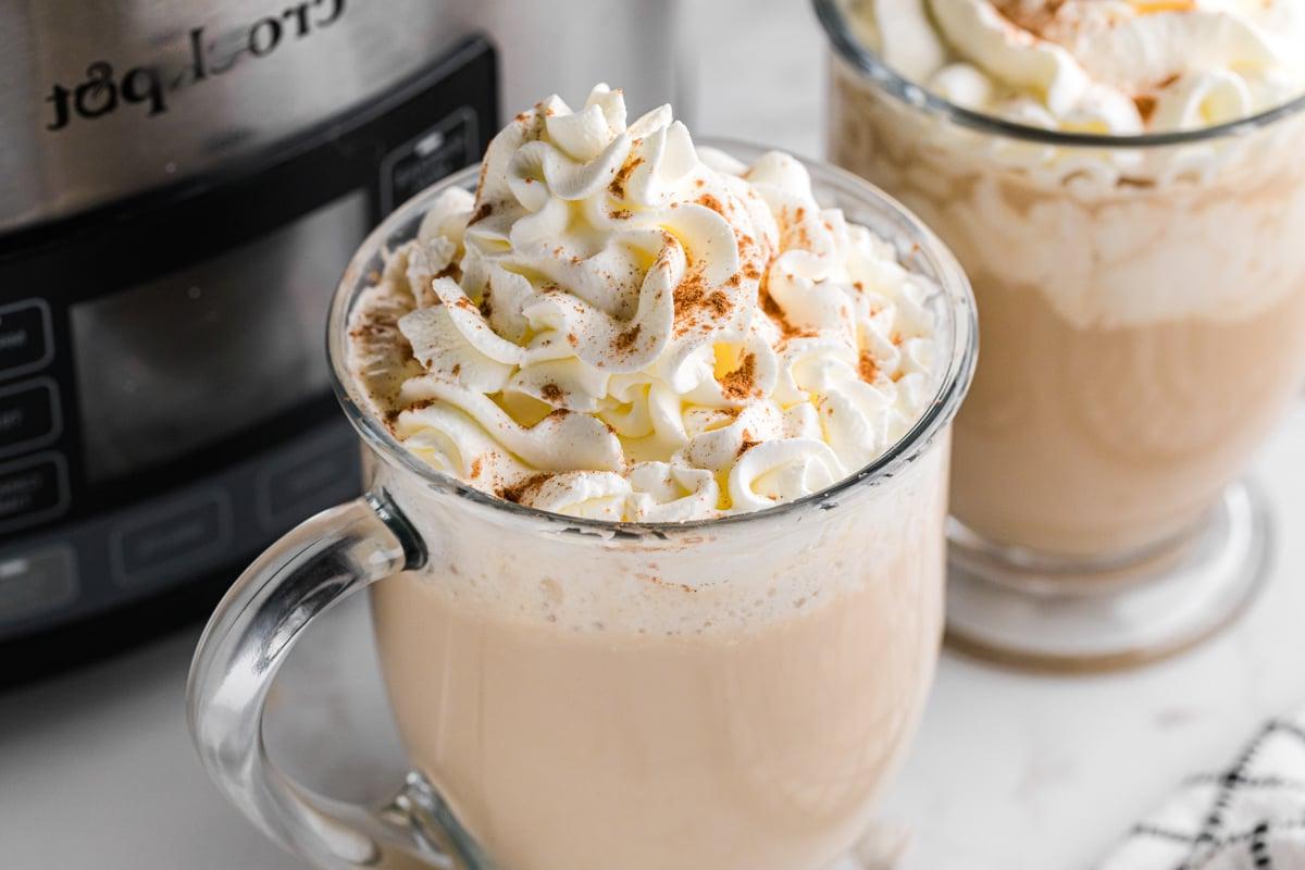 White Russians Caldi a Cottura Lenta 9 White Russian caldi nella pentola a cottura lenta con panna montata in tazze di vetro.