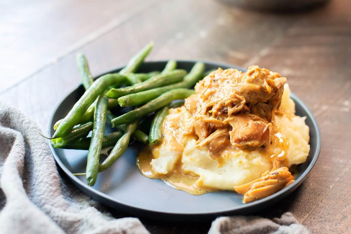 Pollo al Miele e Senape in Pentola a Cottura Lenta 9 Piatto grigio con purè di patate e pollo al miele e senape sfilacciato sopra.