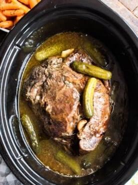 Brasato di manzo cotto con cetriolini sott'aceto sopra.