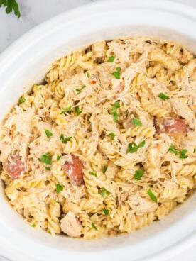 **Pollo all'Aglio e Parmigiano con Pasta a Cottura Lenta** 8 Pasta cremosa al pollo e parmigiano all'aglio nella slow cooker, vista dall'alto in una foto ravvicinata.
