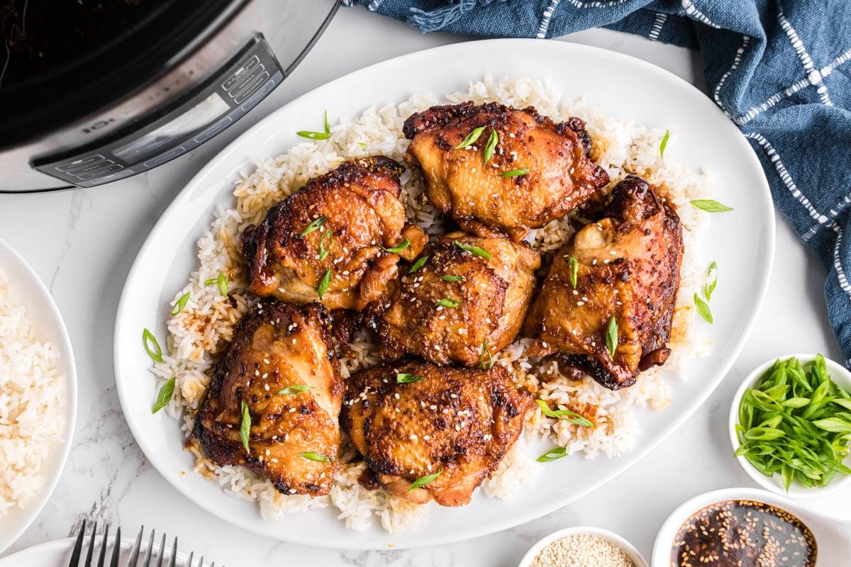 **Cosce di Pollo Teriyaki a Cottura Lenta** 9 Cosce di pollo in slow cooker su un letto di riso su un piatto da portata.