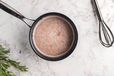 Sugo denso e aromatico per il maiale sfilacciato, a fuoco lento in un pentolino, pronto a sprigionare tutti i suoi profumi.