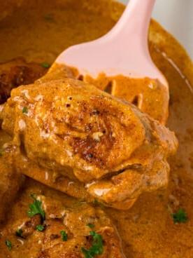 Pollo alla Paprica in Cottura Lenta 10 Un pezzo di pollo alla paprika in slow cooker sollevato con una spatola.