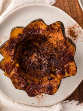 Come Cucinare la Zucca Delica nella Pentola a Cottura Lenta 10 Vista dall'alto di mezza zucca Delica cotta lentamente su un piatto.