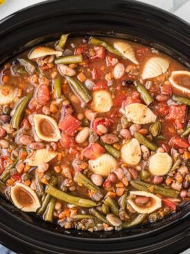 Minestrone di 15 Legumi a Cottura Lenta {Vegetariano} 10 Zuppa minestrone 15 legumi in pentola a cottura lenta con sacchetto di legumi sullo sfondo.