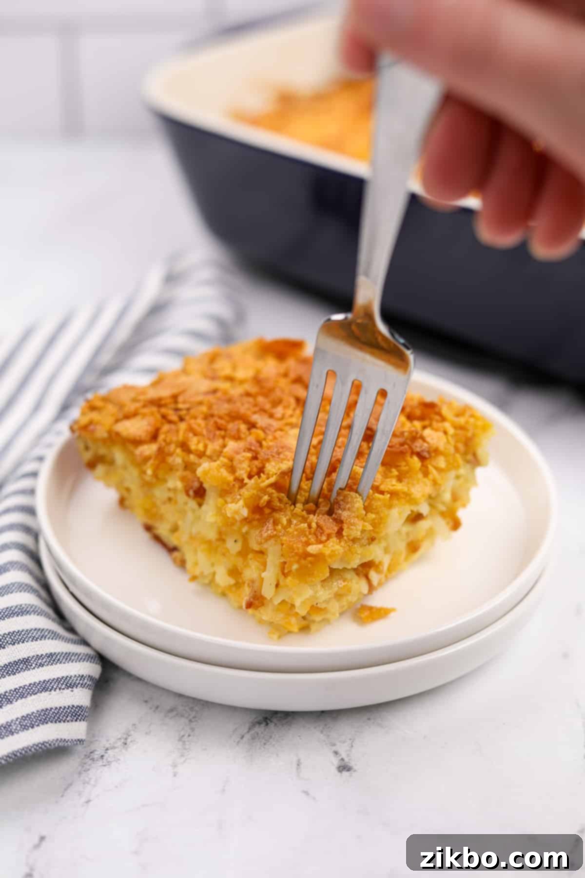 Ultimate Breakfast Hash Brown Bake 6 A fork taking a small portion of breakfast casserole from a plate.