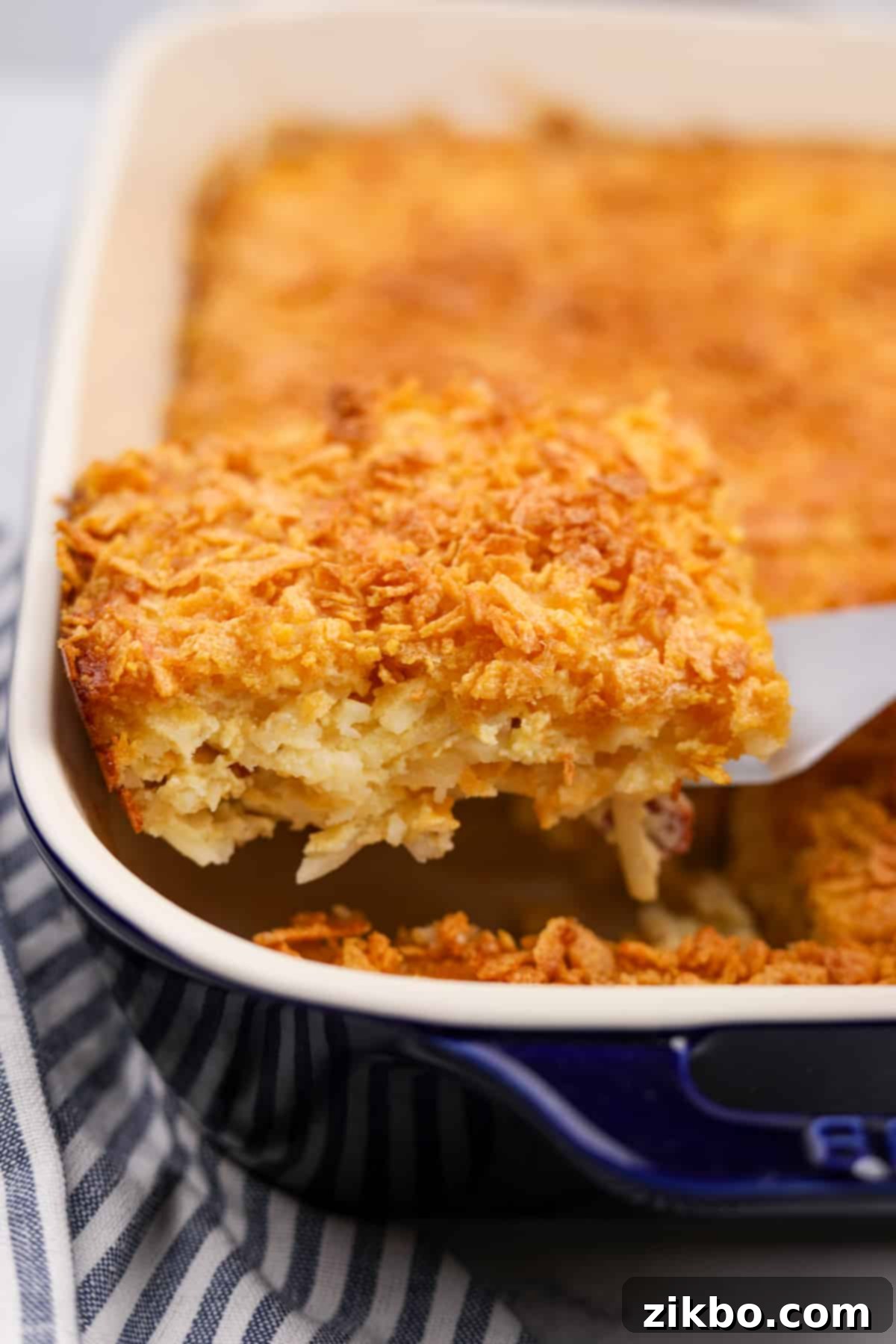 Ultimate Breakfast Hash Brown Bake 7 Lifting a portion of hash brown casserole from a baking dish.