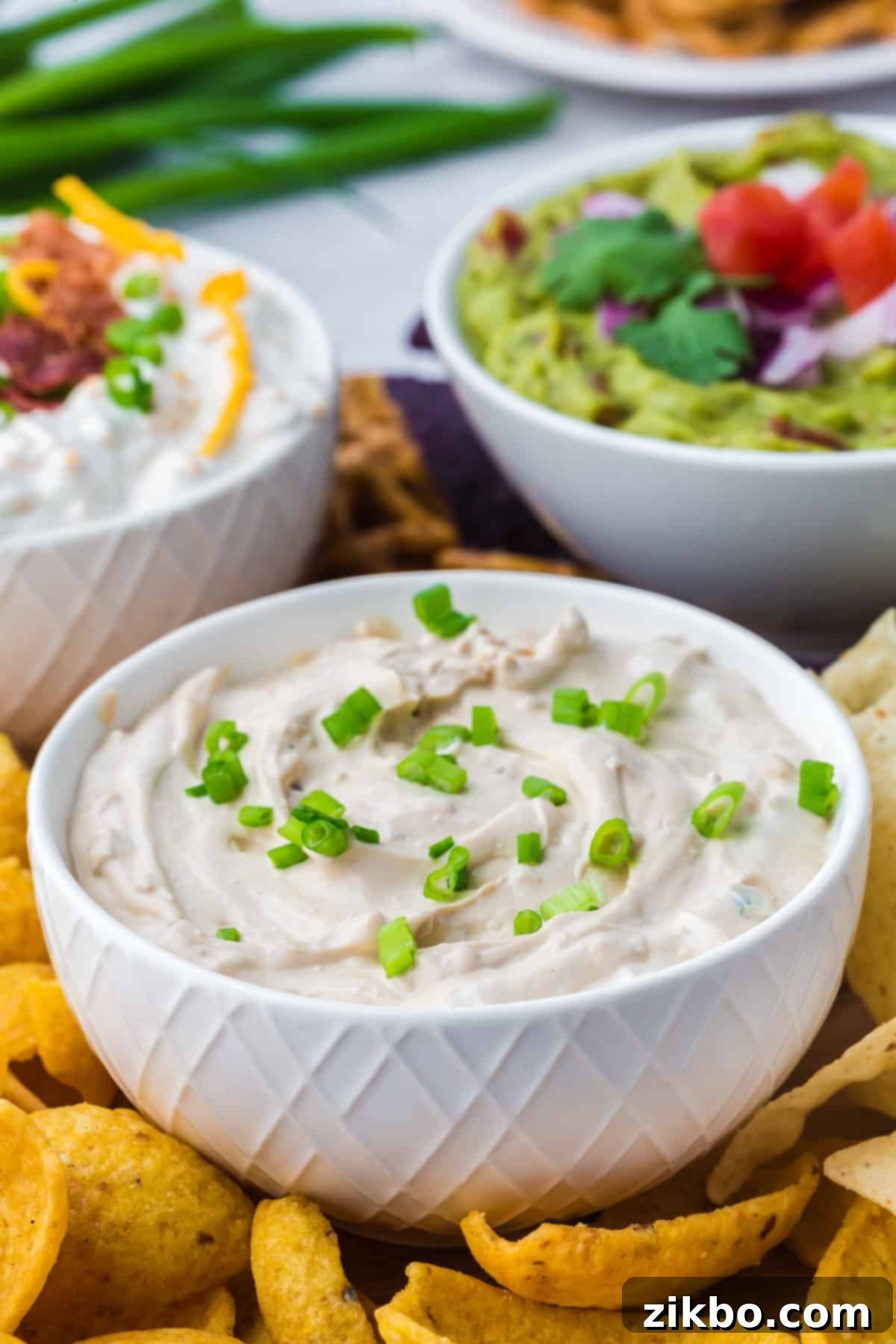 A small bowl of homemade French onion dip garnished with fresh green onions, ready to be served.