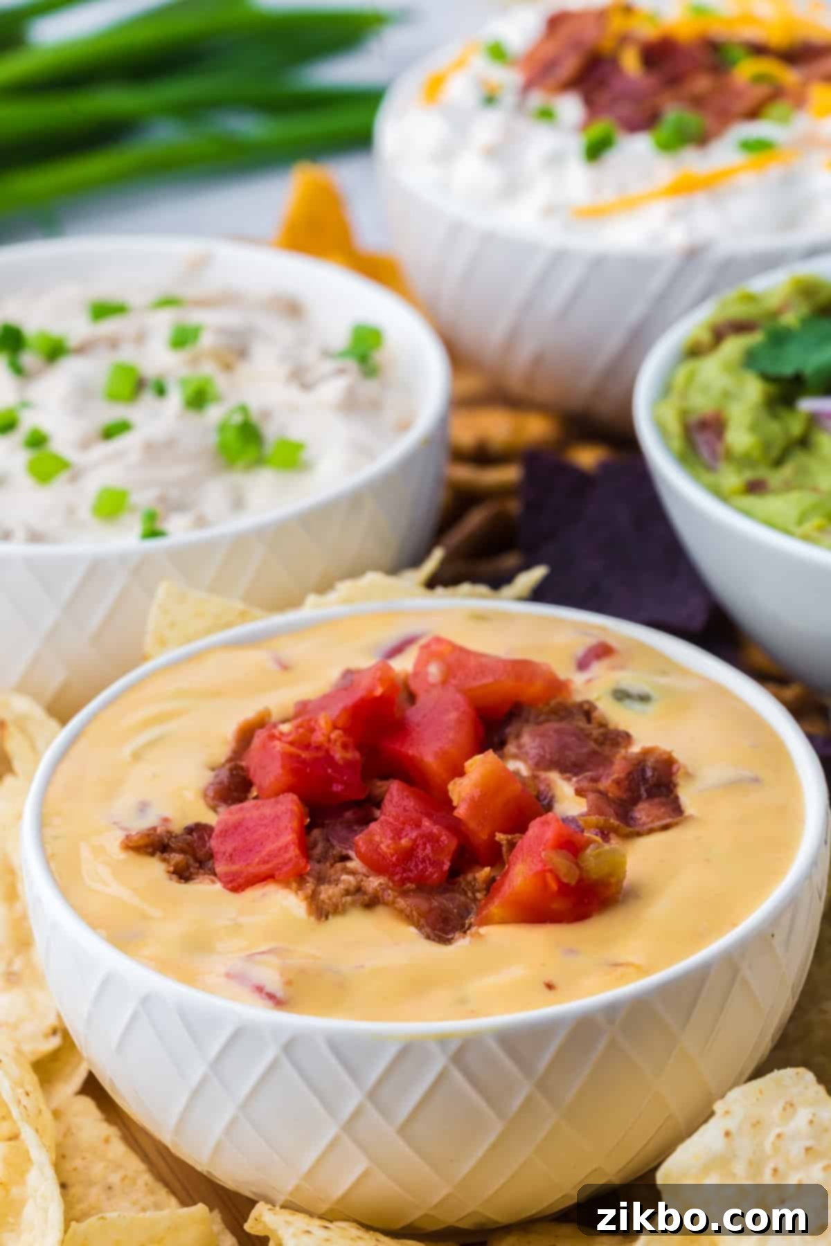A bowl of nacho cheese dip garnished with bacon and tomatoes, ready for serving.