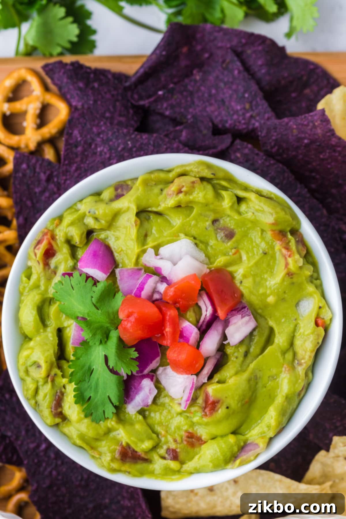 Robust Chunky Guacamole 2 A bowl of guacamole topped with chopped tomato and red onion, ready to be served.