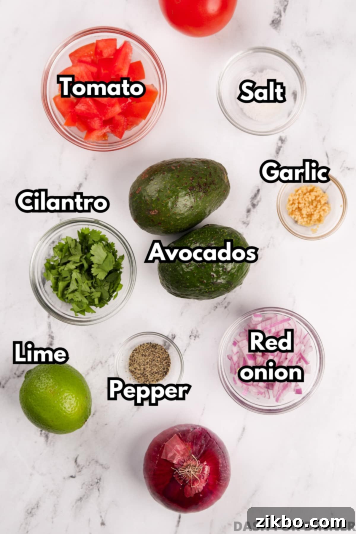 Robust Chunky Guacamole 3 The ingredients needed to make a chunky guacamole dip: tomato, avocado, red onion, cilantro, lime, etc., laid out on a cutting board.