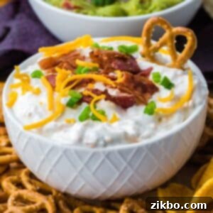Ultimate Loaded Baked Potato Dip 9 A bowl of loaded baked potato dip topped with shredded cheese, bacon, and green onion, ready to be served.