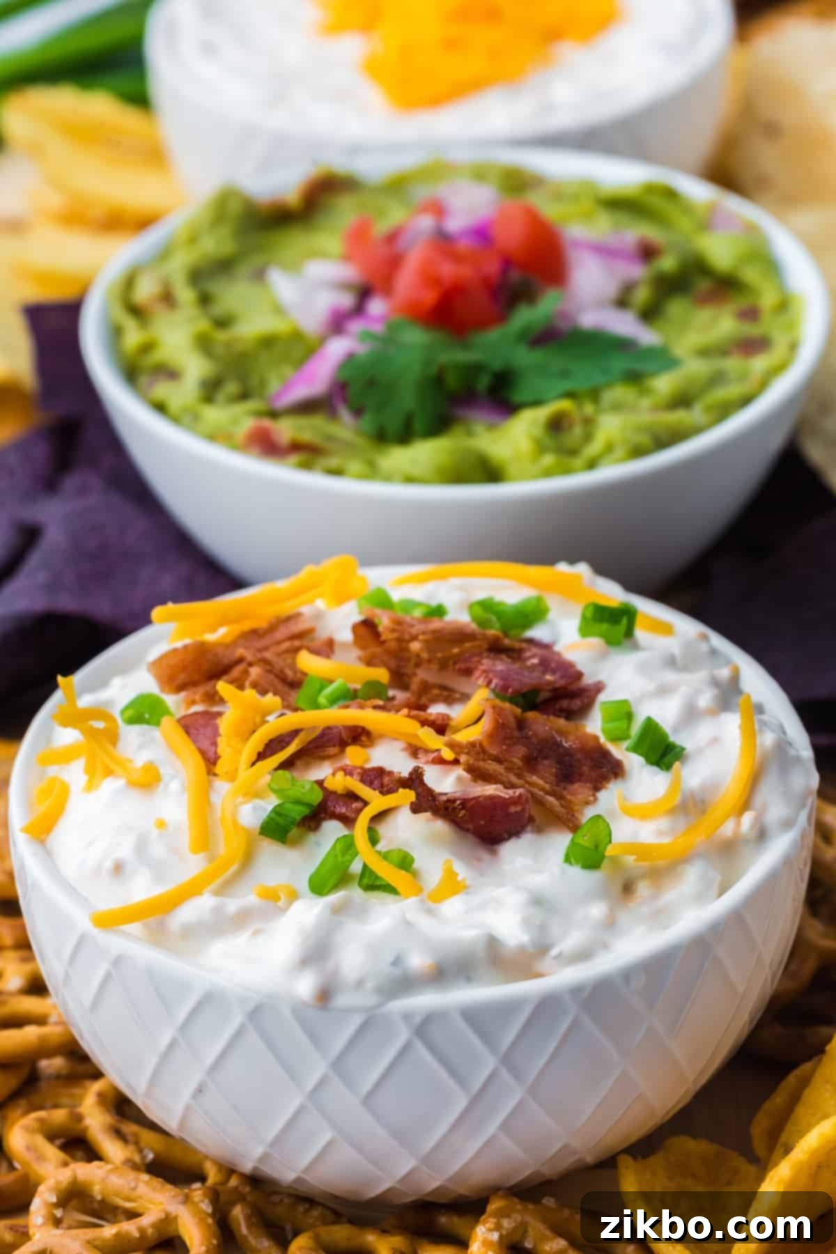 Ultimate Loaded Baked Potato Dip 7 A small white bowl filled with creamy baked potato dip, generously topped with sharp cheddar cheese, crispy bacon, and fresh green onion, ready for serving.
