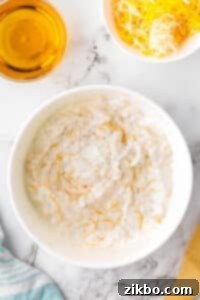A bowl of creamy beer cheese dip in a white bowl, freshly mixed and ready for the next step.