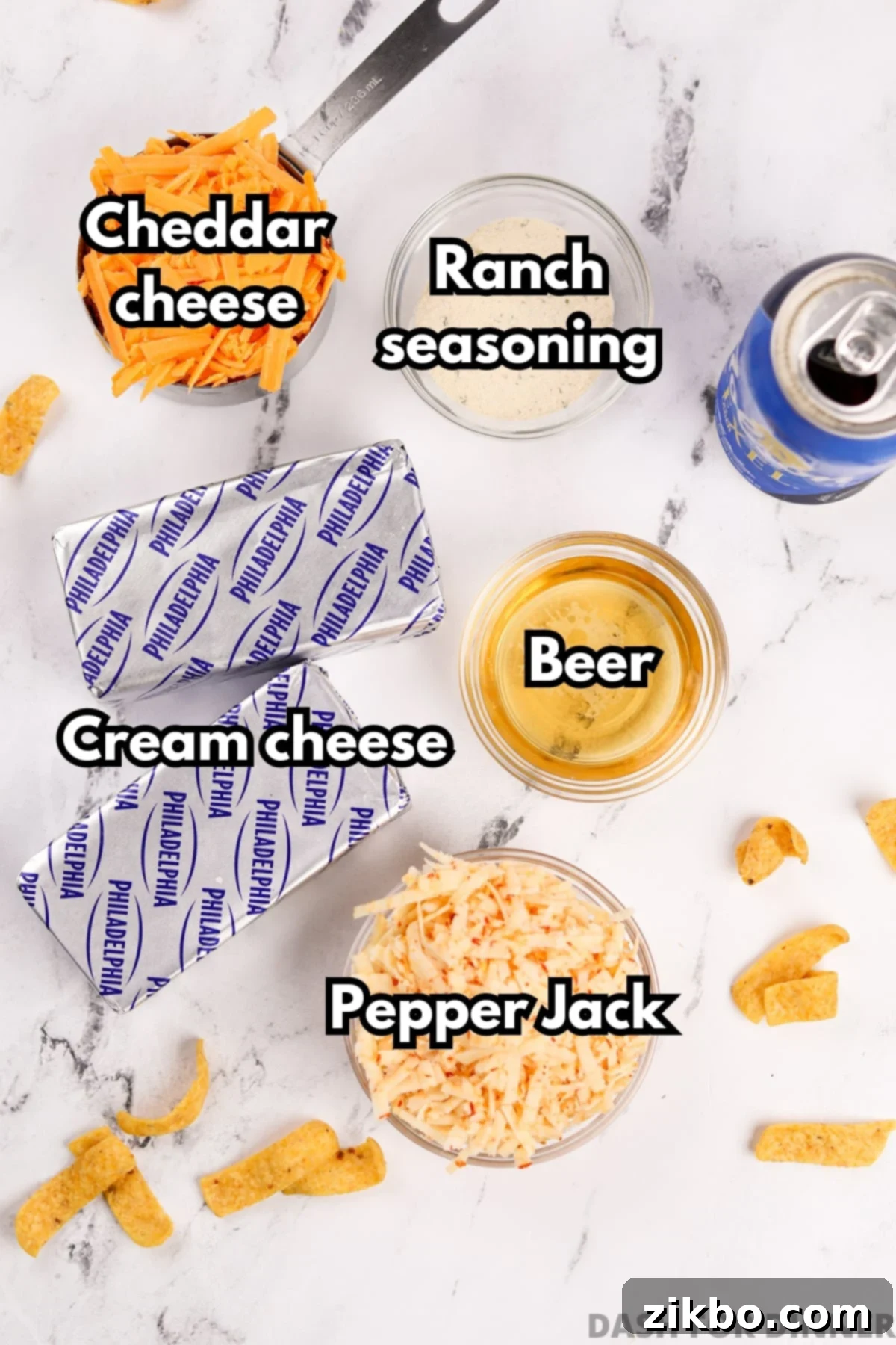 The five key ingredients needed to make beer dip: cream cheese, beer, pepper jack cheese, cheddar cheese, and a packet of ranch seasoning mix.