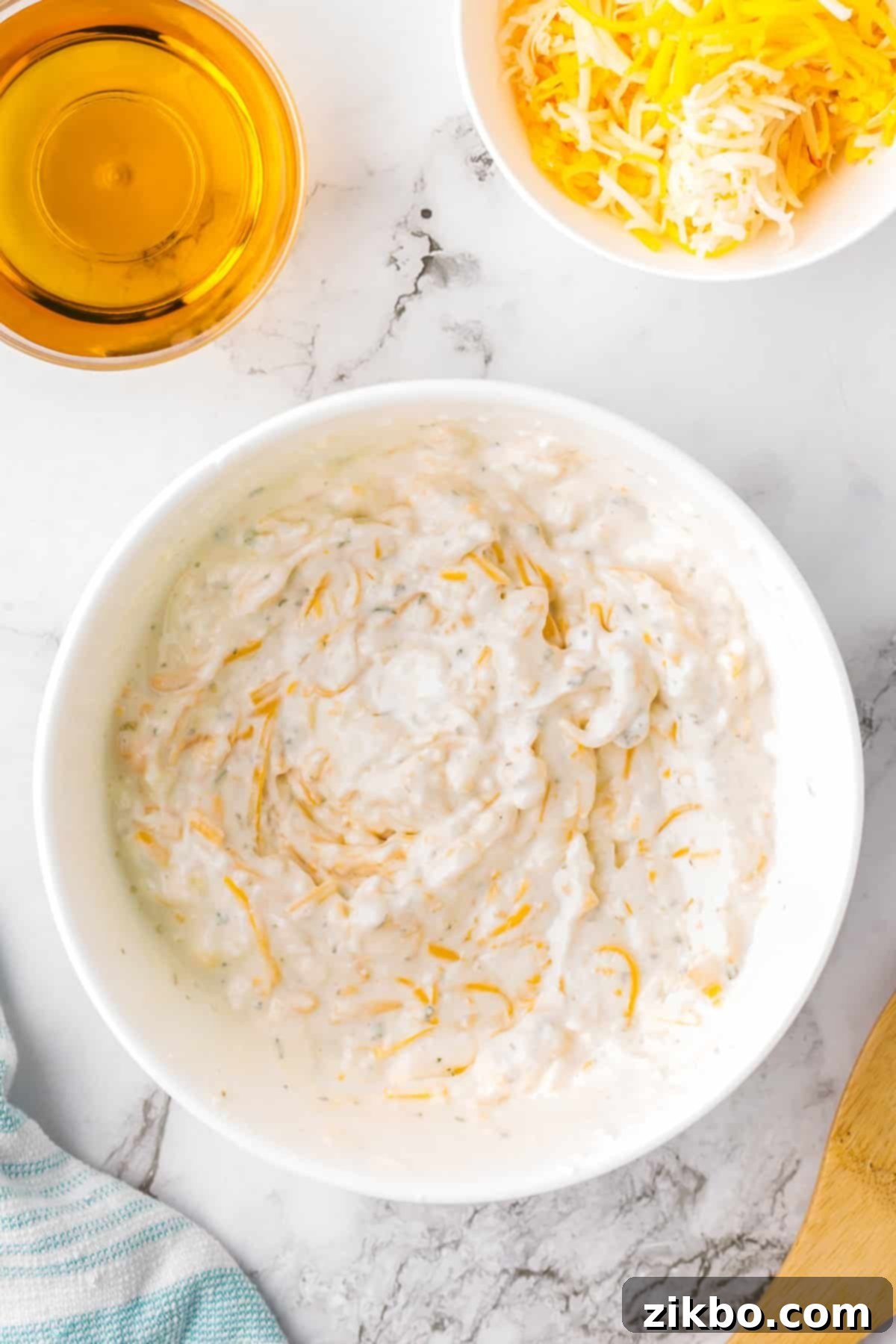 A white bowl containing the creamy, mixed beer cheese dip, ready for chilling or heating.