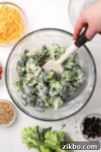 A bowl of broccoli with a creamy dressing poured on top, ready to be mixed into a delicious salad.