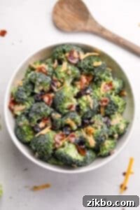 A white bowl filled with finished broccoli salad, garnished beautifully with extra bacon and cheddar cheese for presentation.