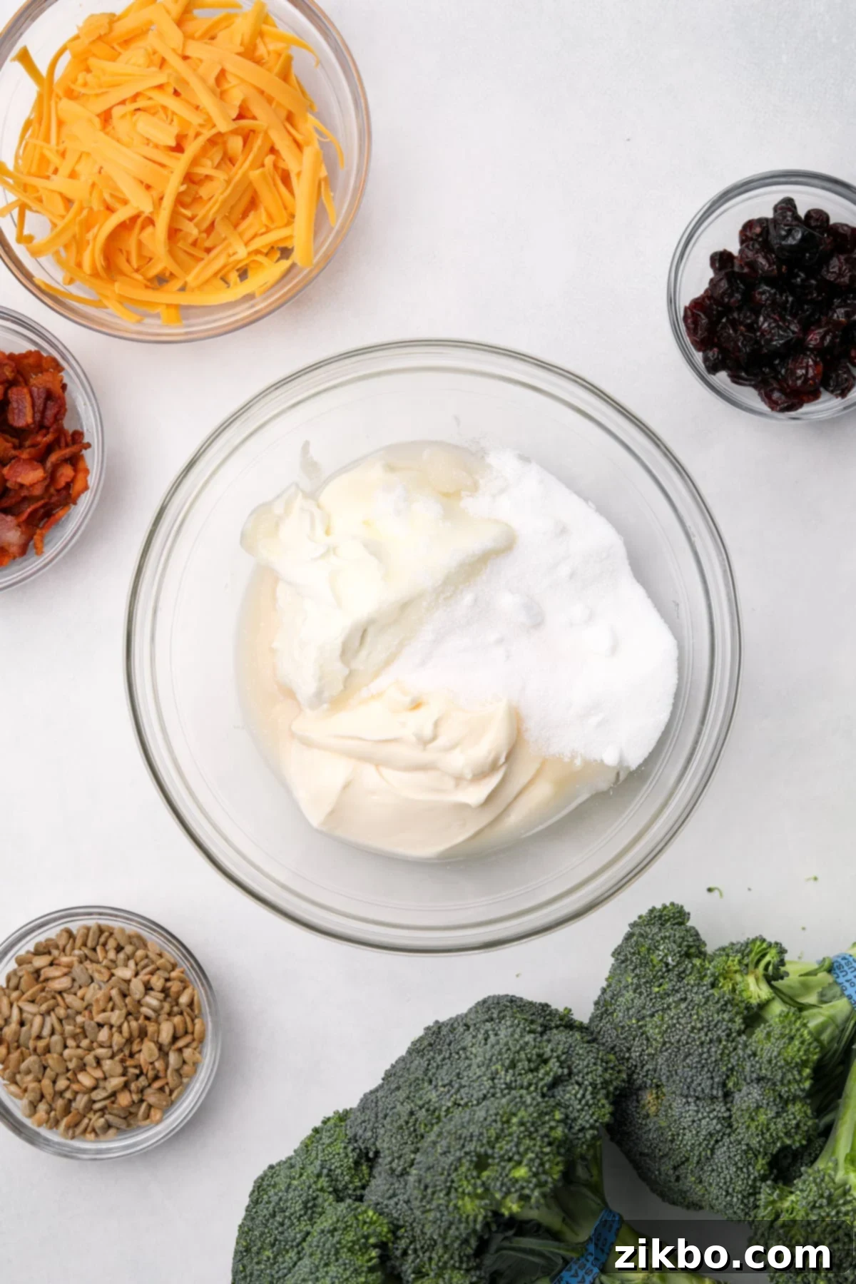 Crunchy Broccoli Delight 4 A medium bowl with a combination of sour cream, mayonnaise, and sugar in it, ready to be mixed for the creamy broccoli salad dressing.