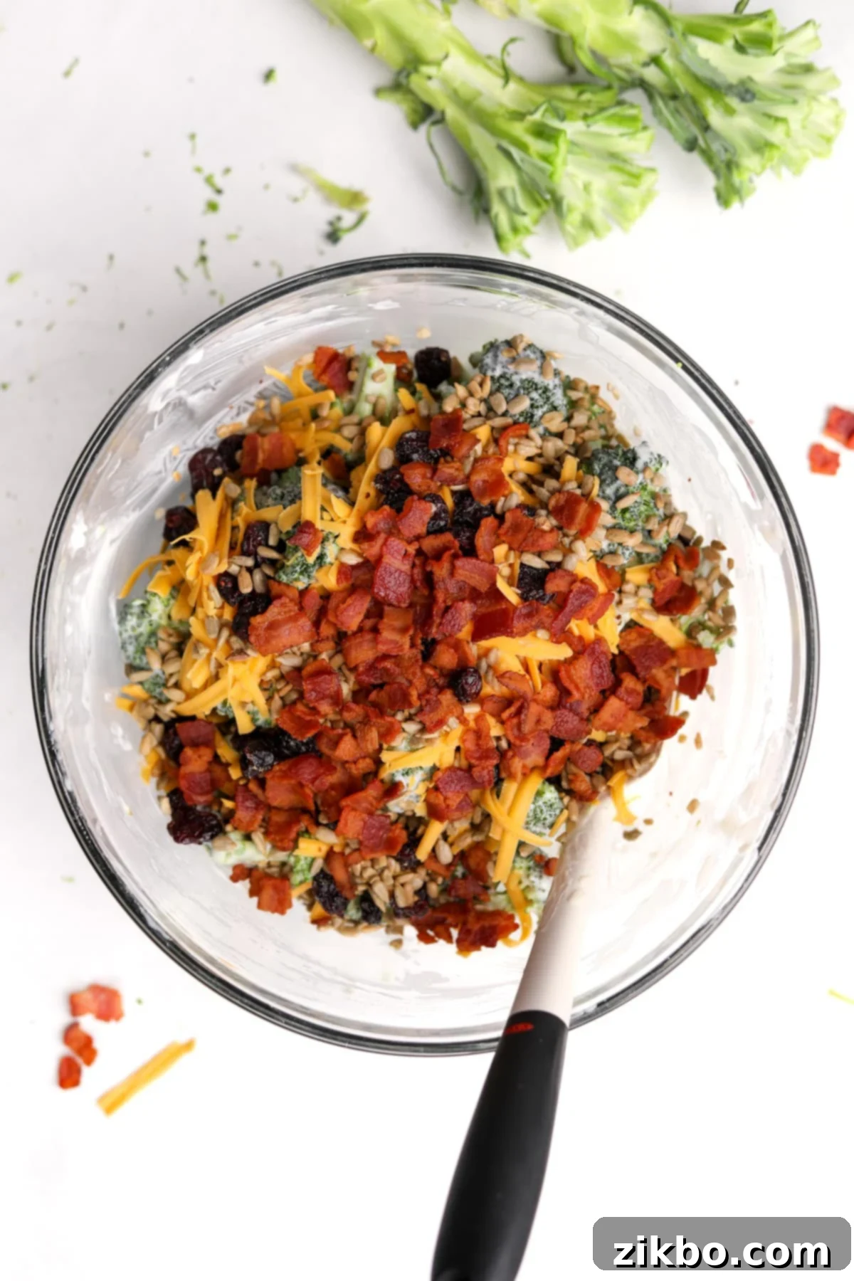 Crunchy Broccoli Delight 9 A bowl of broccoli salad with bacon and cheese mixed in, along with dried cranberries and sunflower seeds.