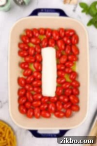 A baking dish filled with cherry tomatoes and a log of goat cheese.
