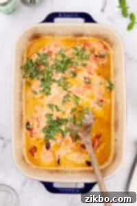 Stirring chopped basil into a creamy sauce in a baking dish.