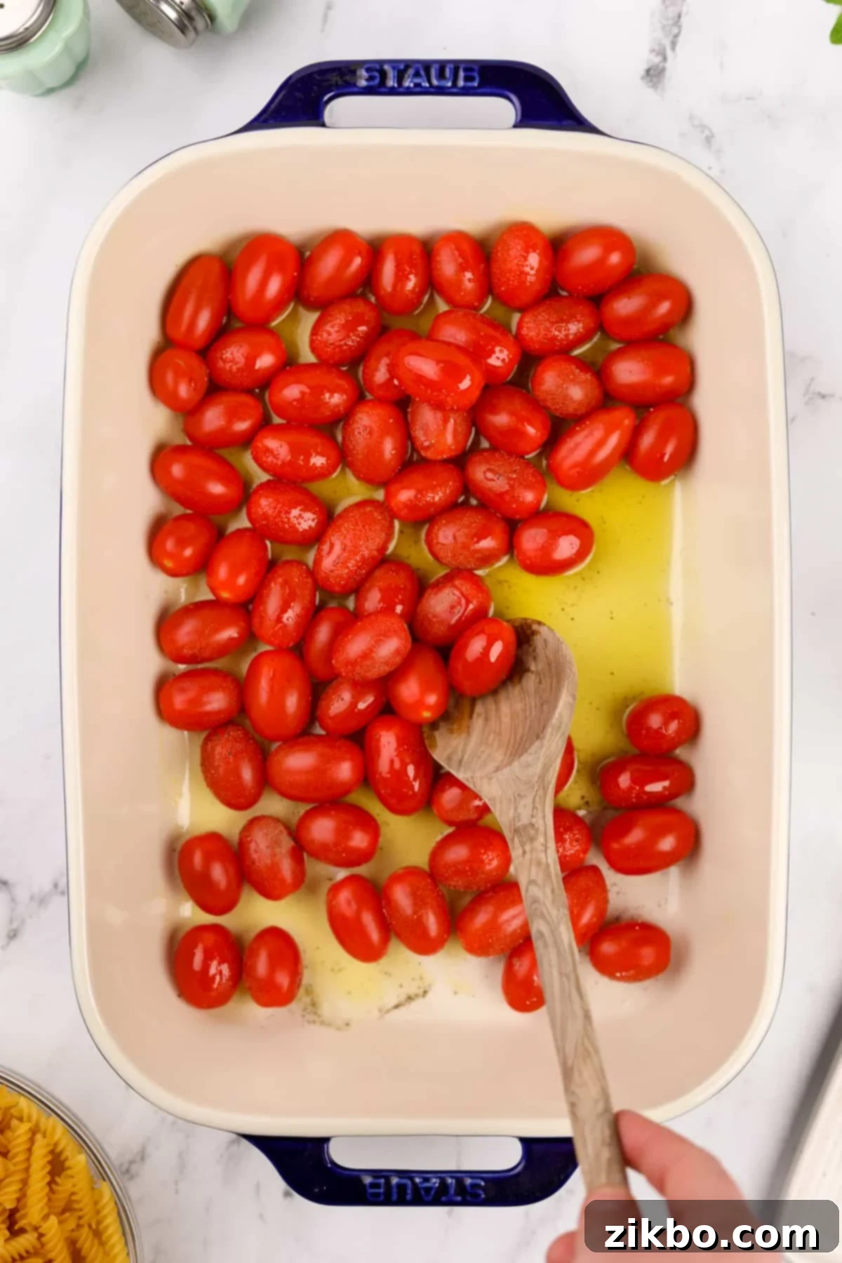 Tangy Goat Cheese Pasta Bake 5 Stirring olive oil and grape tomatoes together in a baking dish, seasoned with salt and pepper.