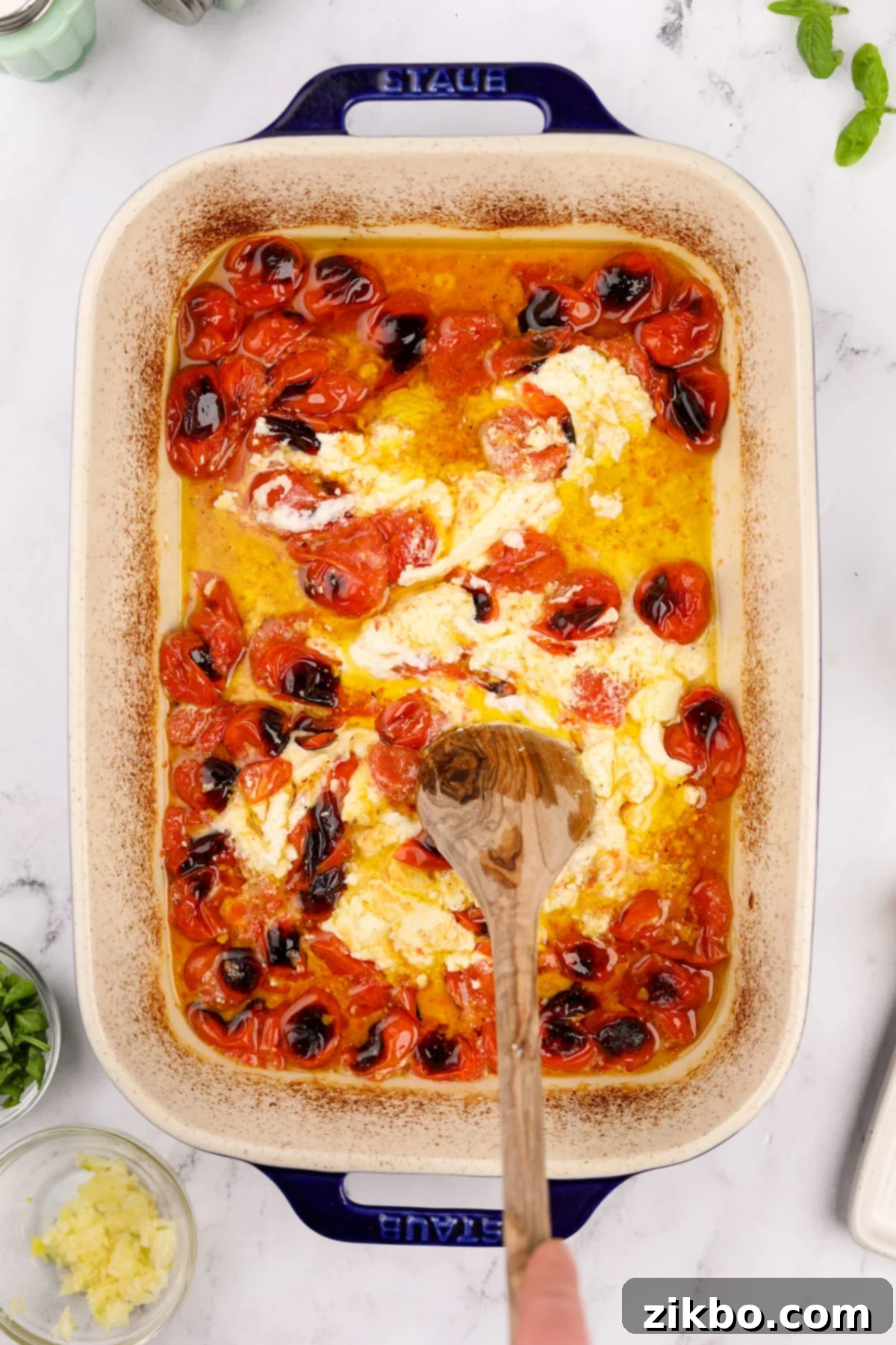 Tangy Goat Cheese Pasta Bake 7 Using a wooden spoon to stir and break up the roasted goat cheese and cherry tomatoes, forming a creamy sauce.