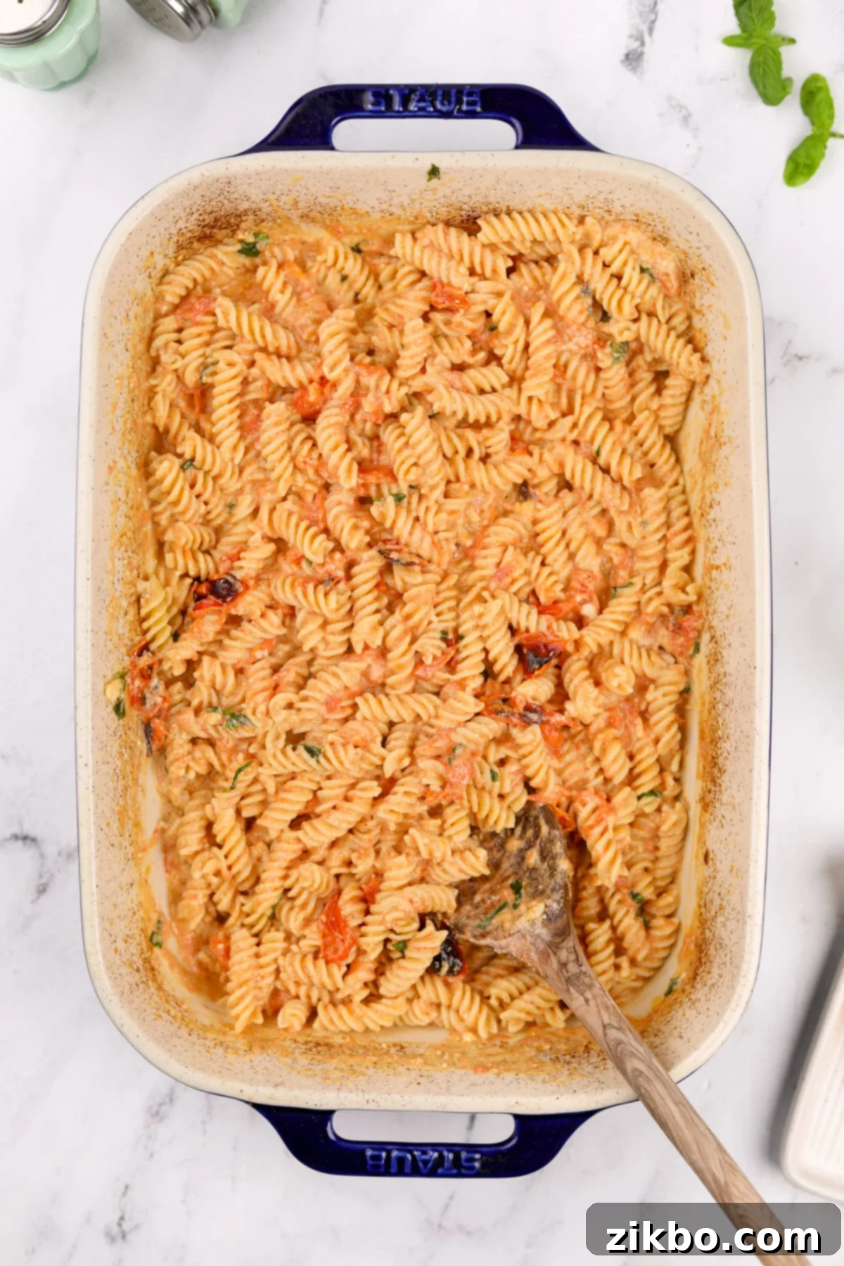 Tangy Goat Cheese Pasta Bake 9 Mixing cooked pasta into the baking dish filled with creamy goat cheese and tomato sauce.