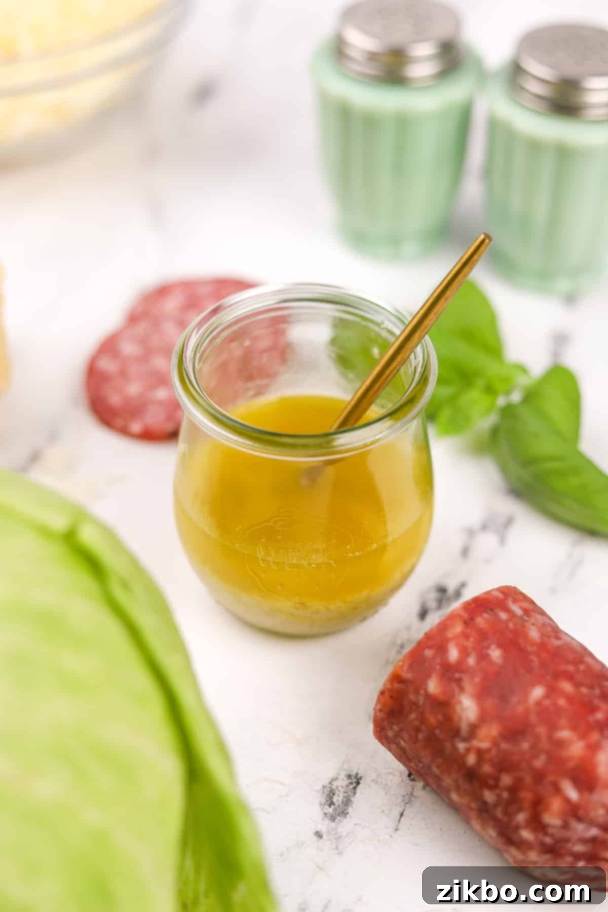 Leon's Artisan Blend 2 A small glass jar filled with a bright, golden Leon salad dressing, ready to be served over a fresh salad.