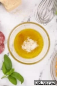 A small bowl with Parmesan cheese, olive oil, and wine vinegar, ready for whisking.
