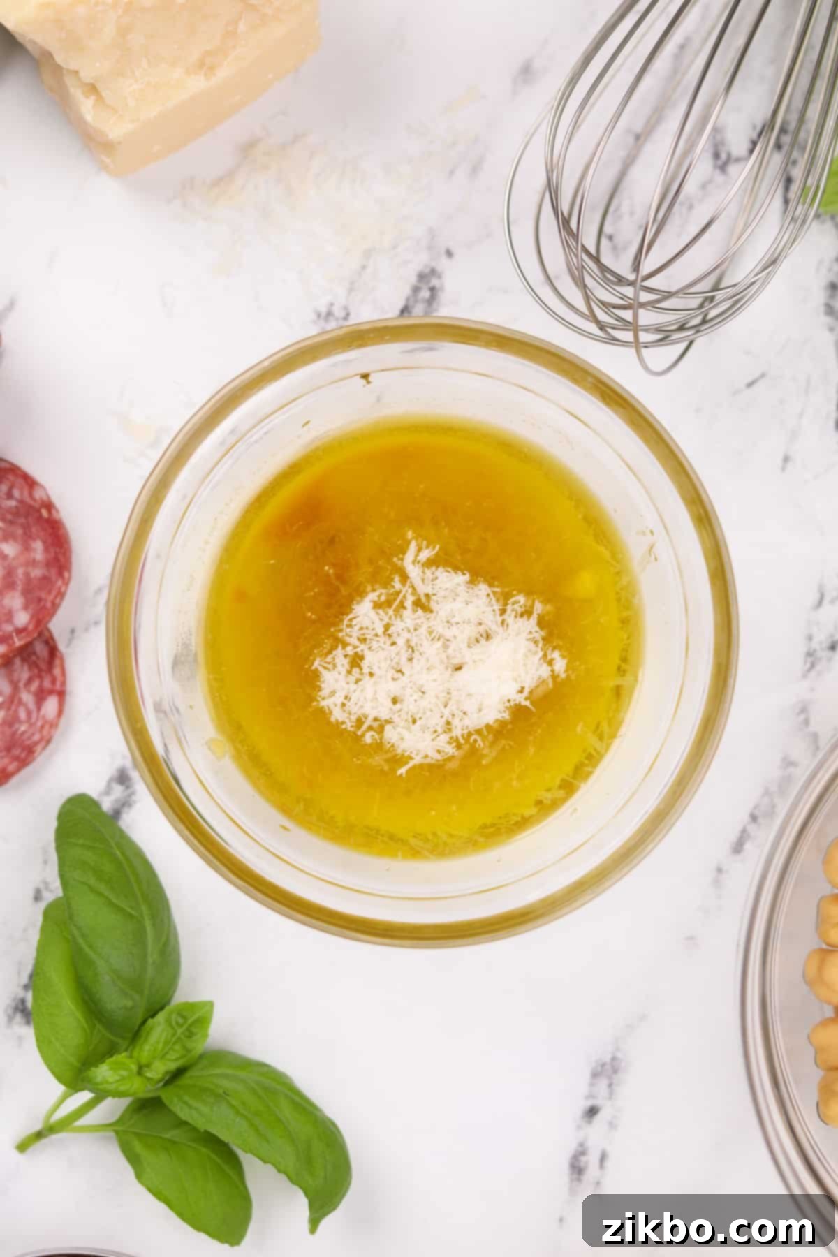 Leon's Artisan Blend 4 A small bowl containing extra virgin olive oil, white wine vinegar, and finely grated Parmesan cheese, ready to be mixed for the dressing.