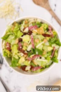 A large bowl of the finished chopped Italian Salad with sliced salami and mozzarella, ready to serve.