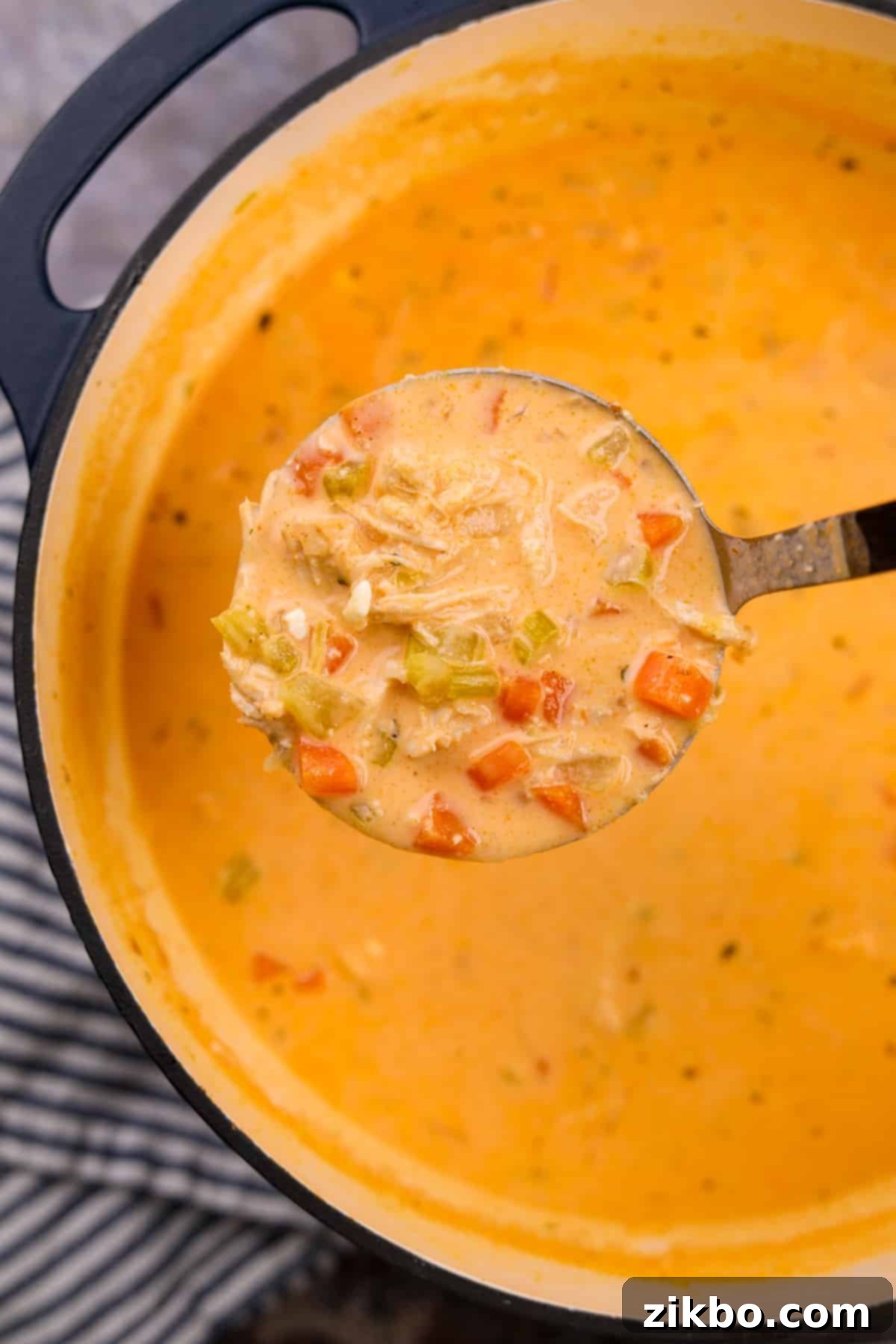 Bold Buffalo Chicken Soup 7 A ladle scooping a creamy portion of buffalo chicken soup from a large Dutch oven.