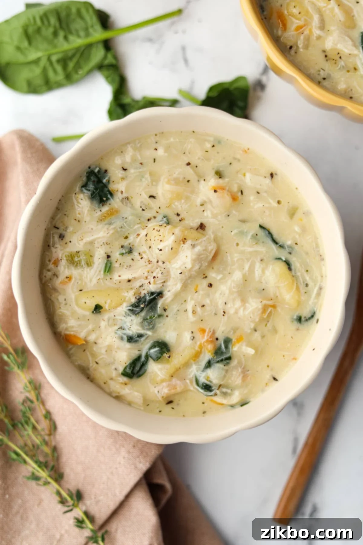 Comforting Creamy Chicken Gnocchi Soup 2 A beautiful bowl of creamy chicken and gnocchi soup, garnished with fresh spinach and herbs.