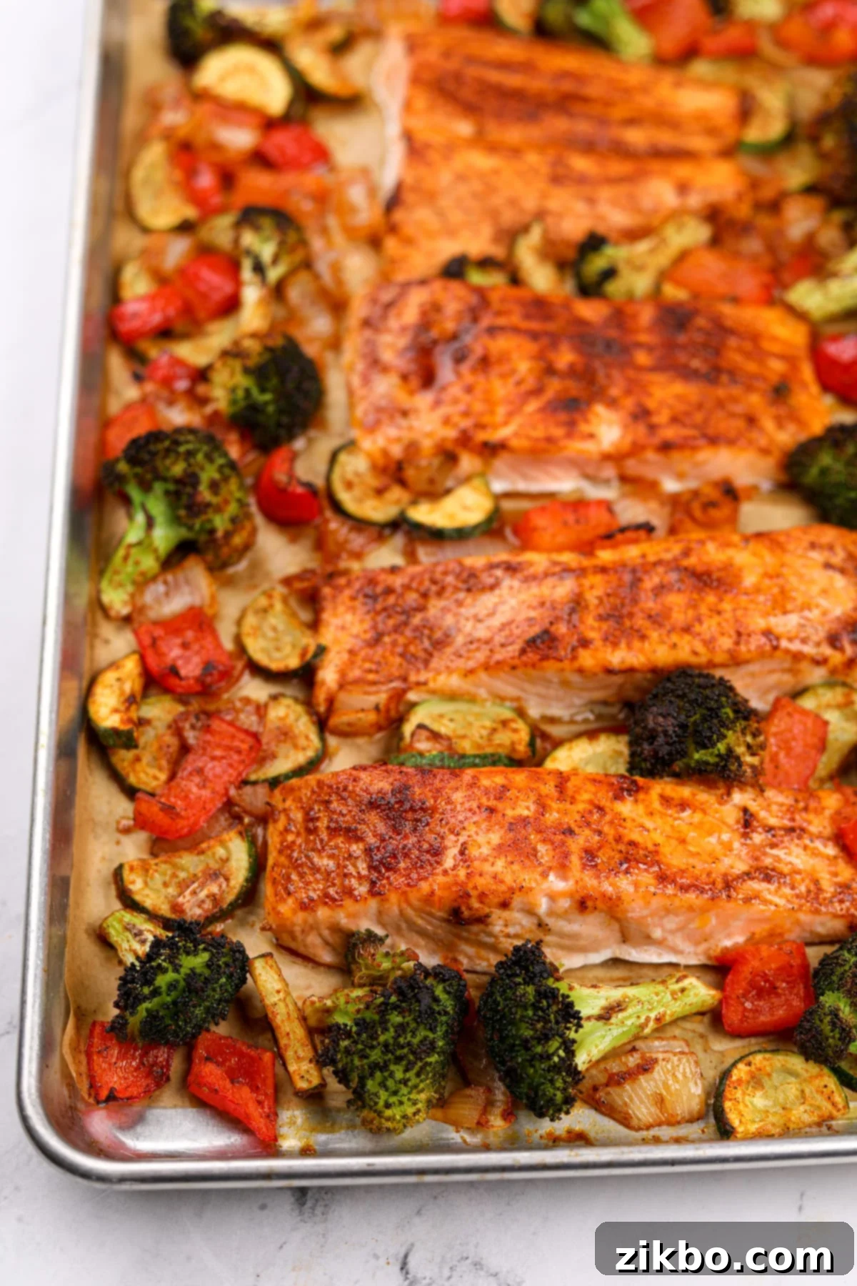 Effortless Sheet Pan Salmon Feast 12 An overhead view of an entire sheet pan generously filled with perfectly roasted salmon fillets and a vibrant assortment of broccoli, bell pepper, and zucchini, ready to be served.