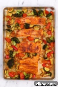 A sheet pan with roasted vegetables and salmon fillets.