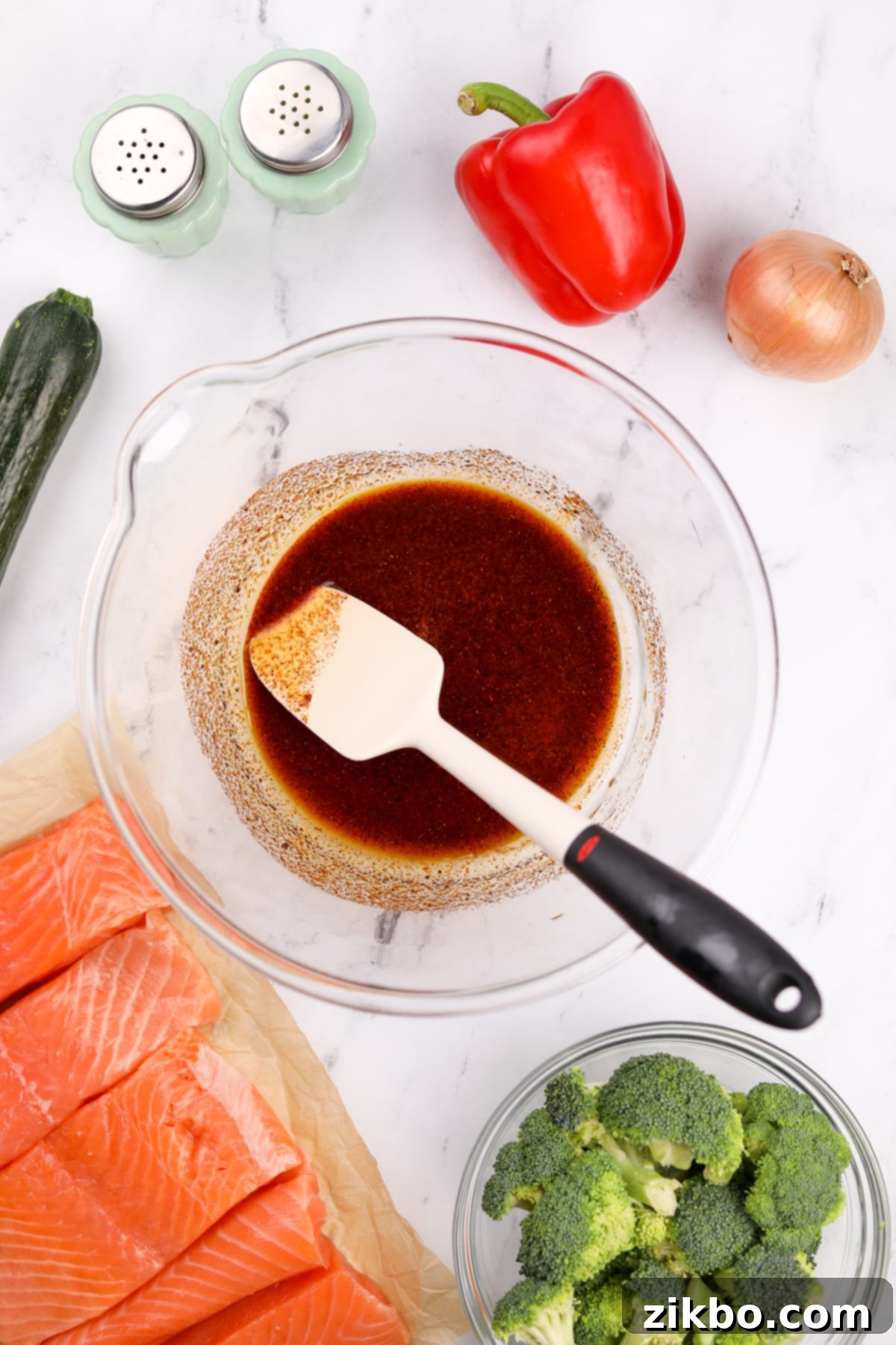 Effortless Sheet Pan Salmon Feast 4 A large mixing bowl filled with olive oil, lemon juice, paprika, garlic powder, salt, and pepper, all whisked together to create a flavorful seasoning blend.
