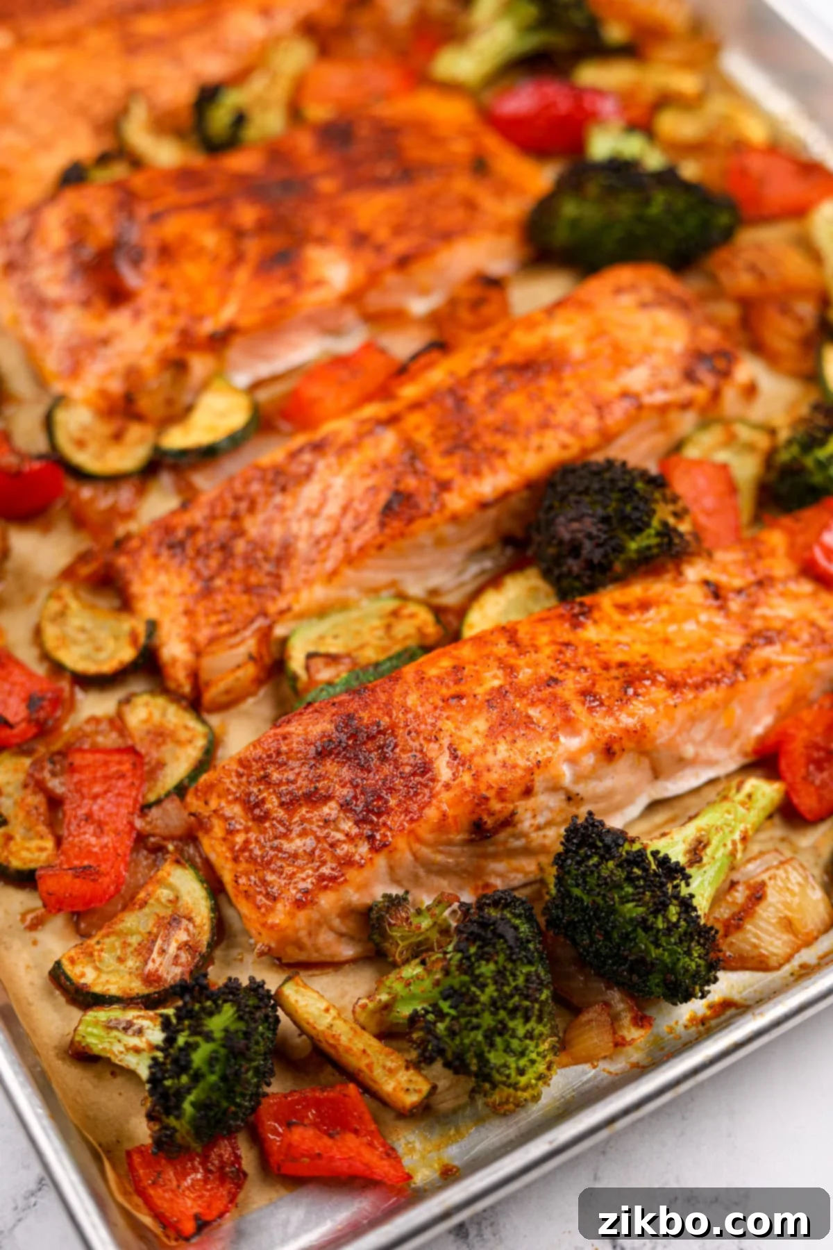 Effortless Sheet Pan Salmon Feast 10 A close-up of beautifully seasoned and roasted salmon fillets nestled among vibrant, tender-crisp vegetables on a baking sheet, fresh from the oven.