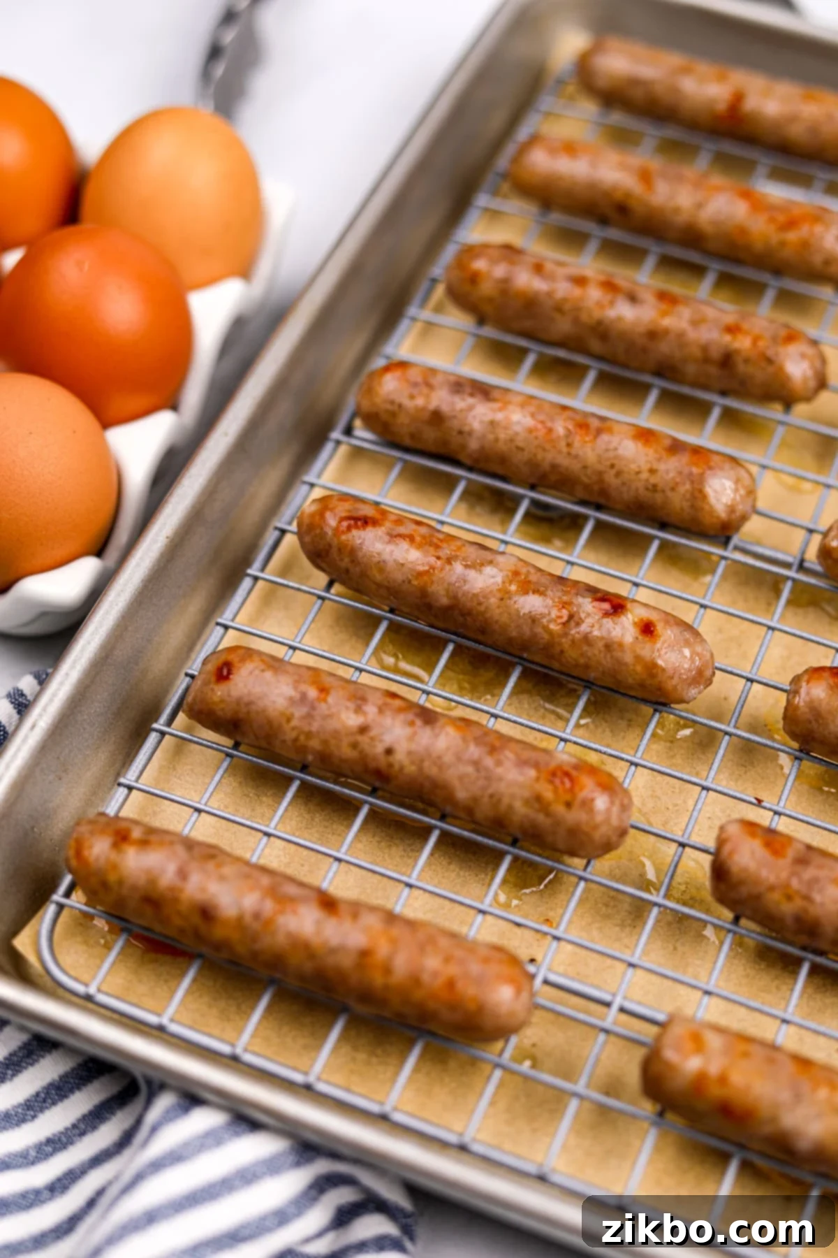 A close-up of beautifully baked breakfast sausages arranged neatly on a wire rack, which is set on a baking sheet, showcasing their golden-brown color and appealing texture.