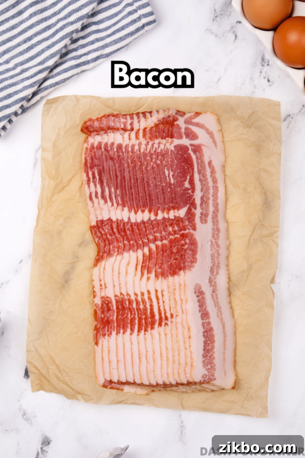 Perfectly Crispy Baked Bacon 3 Multiple slices of bacon on a piece of parchment paper on a marble counter.