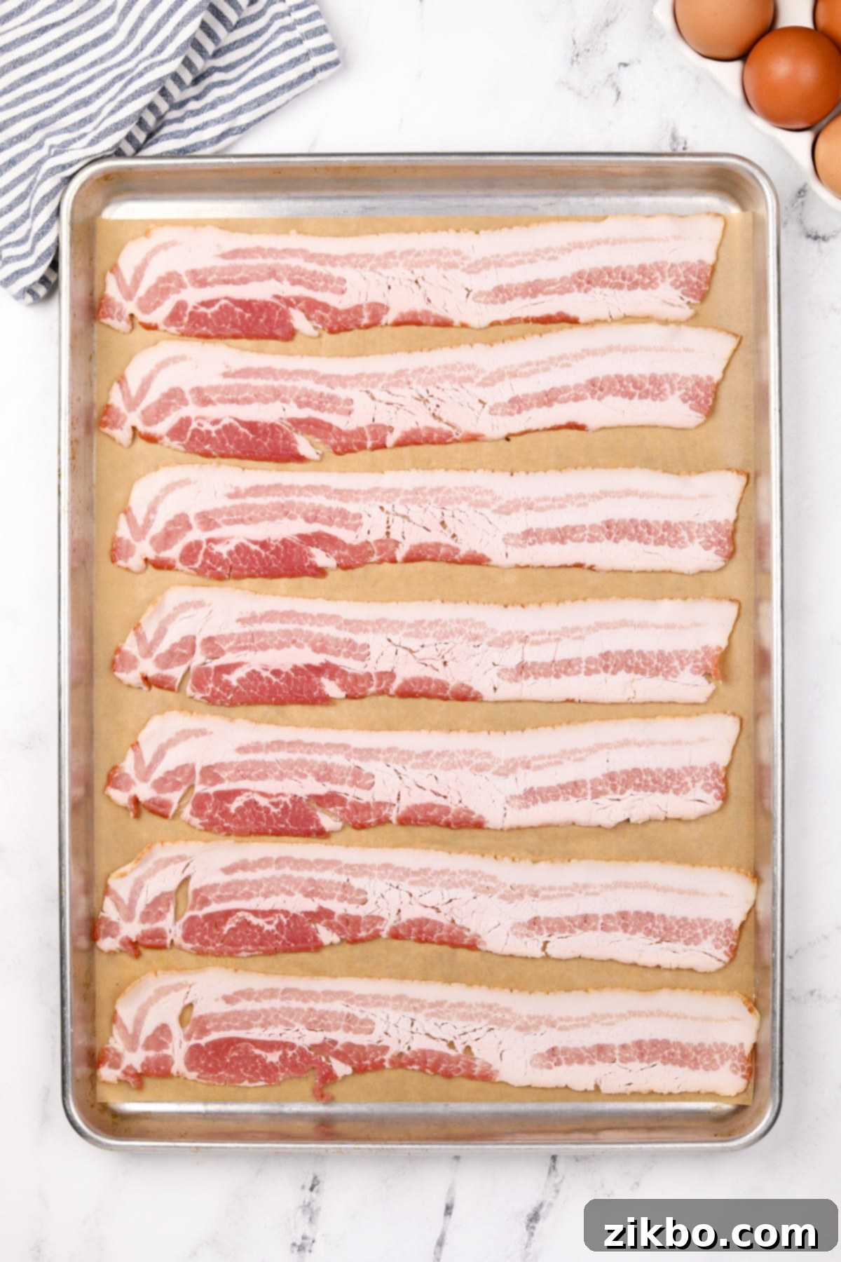 Perfectly Crispy Baked Bacon 4 Eight slices of bacon on a parchment lined baking sheet.