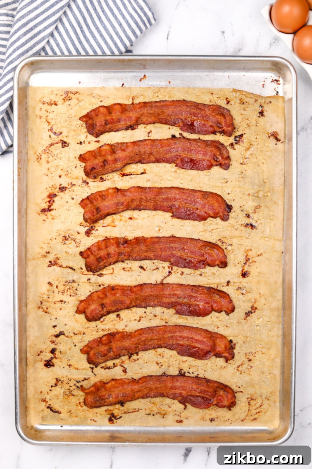 Perfectly Crispy Baked Bacon 5 A baking sheet with 8 slices of bacon that have been cooked until crispy.
