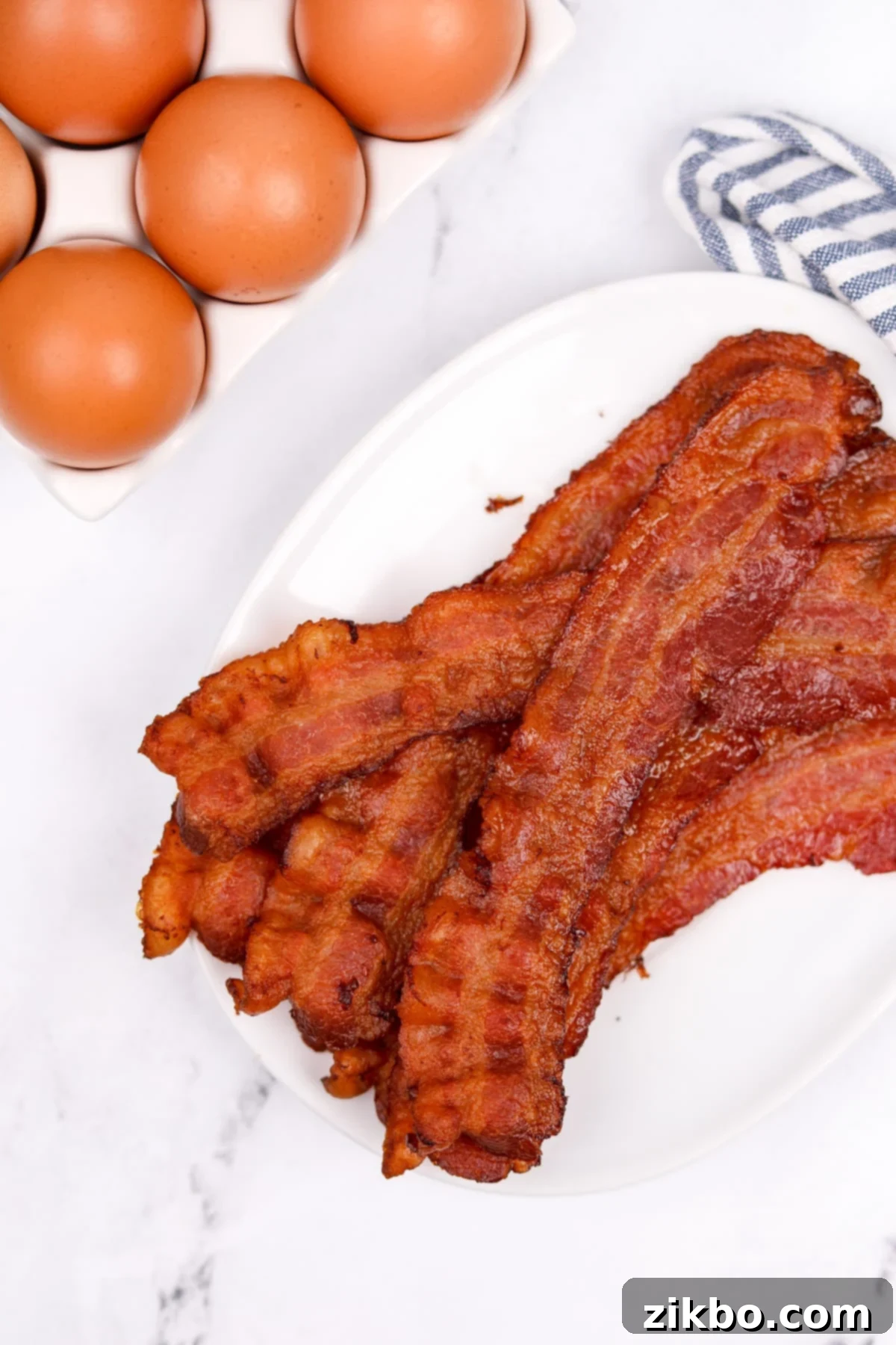 Perfectly Crispy Baked Bacon 8 Crispy bacon on a white plate.