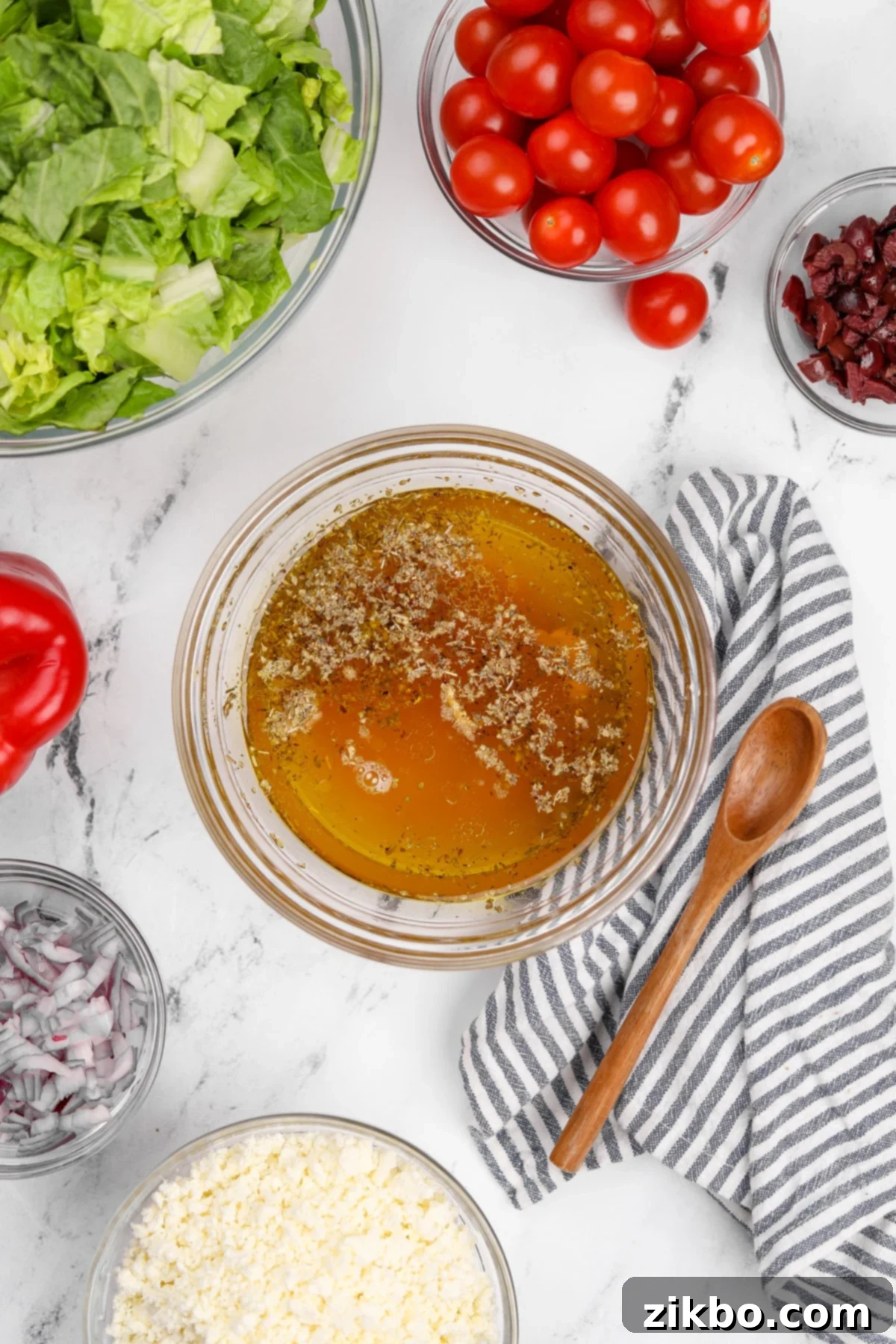All the Greek vinaigrette ingredients combined in a small bowl, ready to be whisked together.