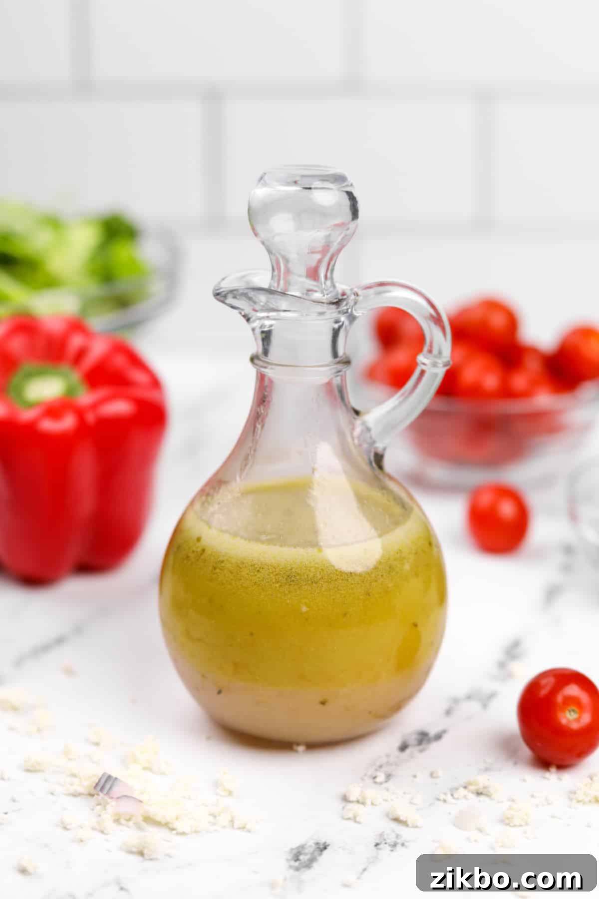 A salad dressing cruet filled halfway with a golden olive oil-based Greek dressing, ready to be served.