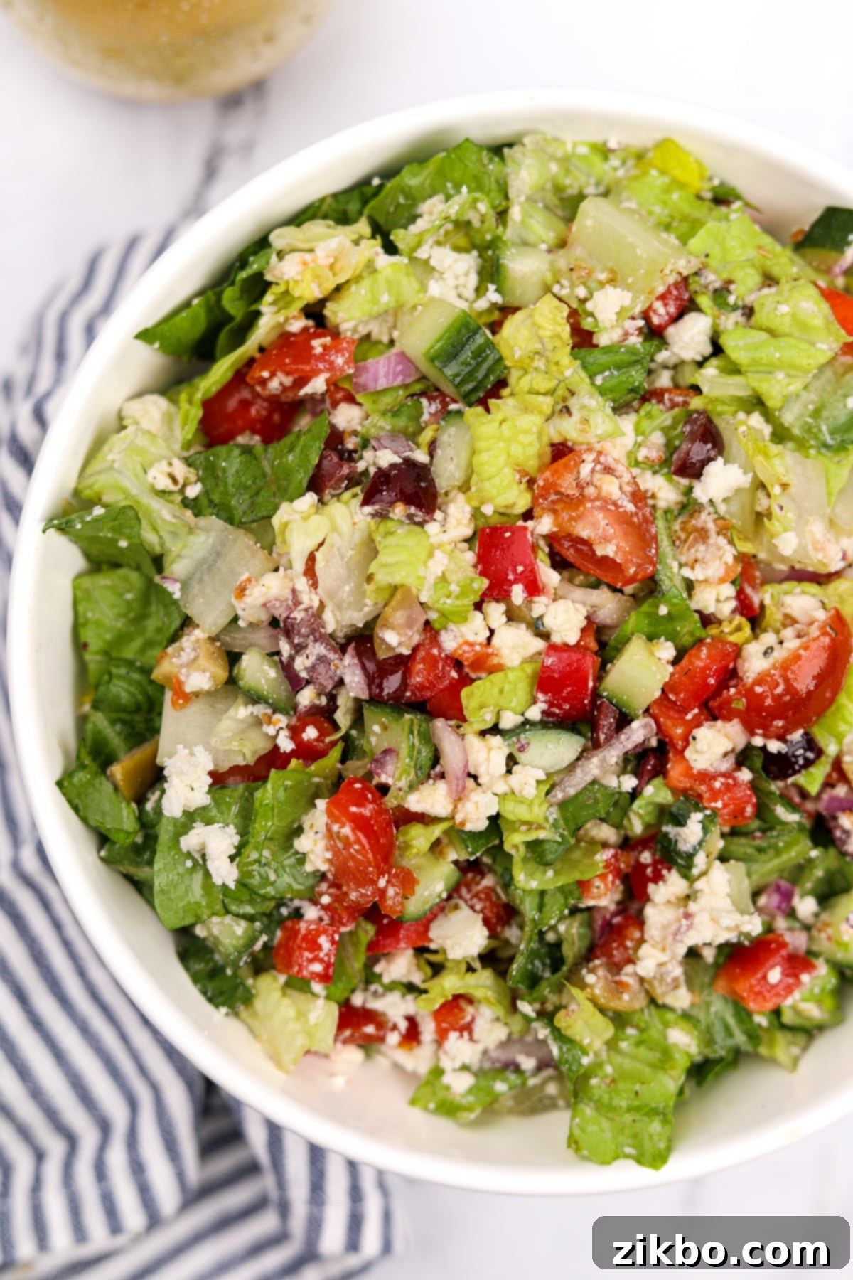 The Perfect Greek Chopped Salad 2 A vibrant bowl of green chopped salad generously topped with crumbled feta, black and green olives, crisp cucumbers, and ripe cherry tomatoes.